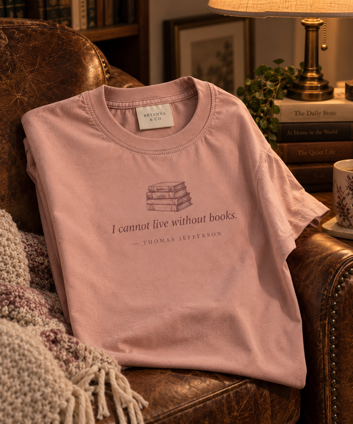 Dusty Rose relaxed-fit tee printed with “I cannot live without books.” in mauve serif type, folded on a linen backdrop
